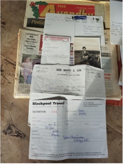 A collection of various documents and papers laid out on a surface, including old newspapers, travel quotations, and personal correspondence.